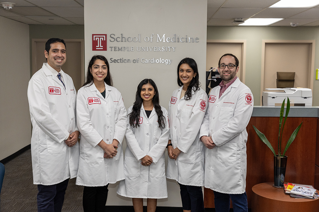 Second Year Fellows in white coats, 3 men and 2 women, smiling