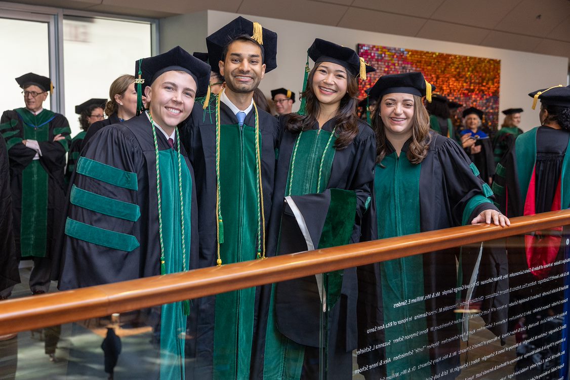 A group of smiling students wearing graduation gowns