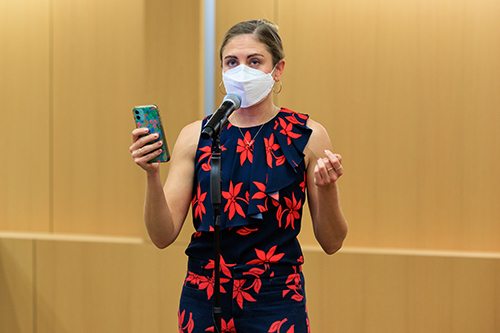 a woman in a face mask reading aloud from her phone at the Story Slam