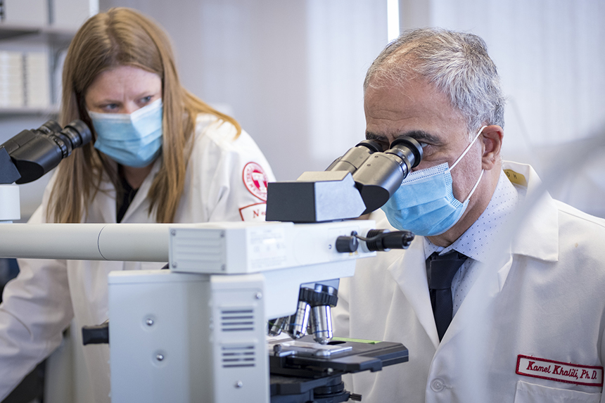  Kamel Khalili, PhD and Tricia H. Burdo, PhD looking into microscopes in a lab