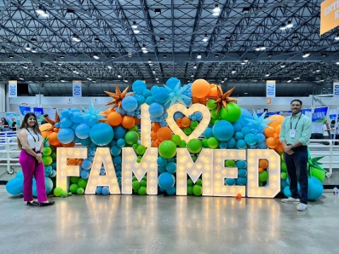 A resident poses with a balloon display that reads "I love family medicine"