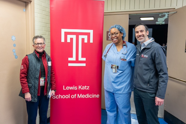 Dr. Goldberg poses with two practitioners in front of a Lewis Katz School of Medicine banner
