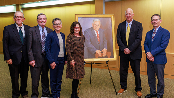 six male and female doctors in front of a portrait of Wallace P. Ritchie Jr., MD