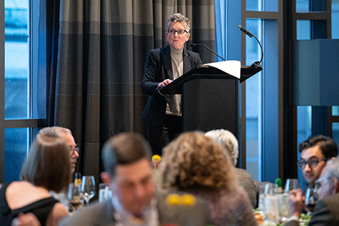 Dr. Amy Goldberg giving a speech at a podium in front of the dinner guests