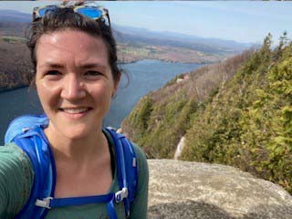 Nora Stedman on a mountain with a body of water in the background