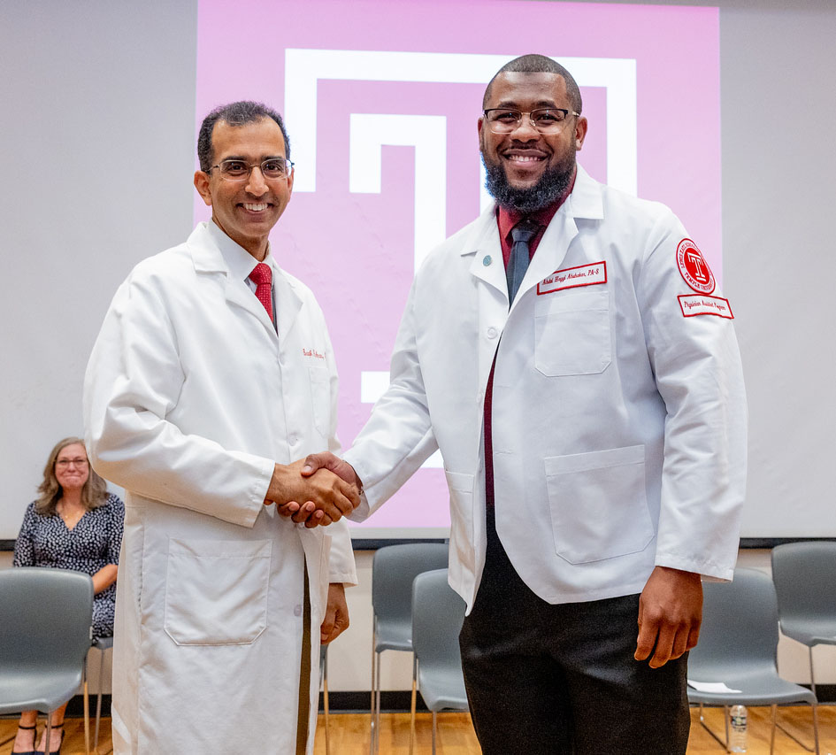 Two people shaking hands wearing white coats