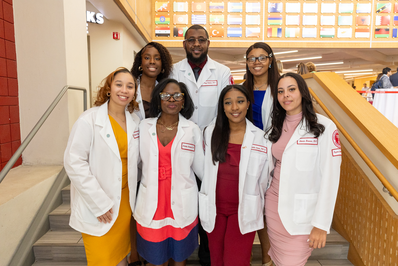 Seven students in white coats look into the camera 