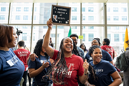 a female medical student holding up a sign that says "I matched OBGYN at UCSFI