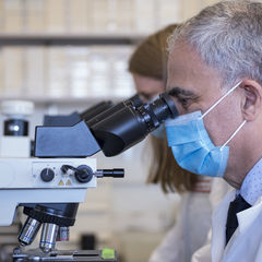Kamel Khalili, PhD staring in a microscope