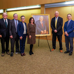 six male and female doctors in front of a portrait of Wallace P. Ritchie Jr., MD