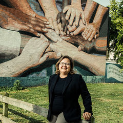 Dr. Kathleen Reeves in front of a mural of people touching their hands together
