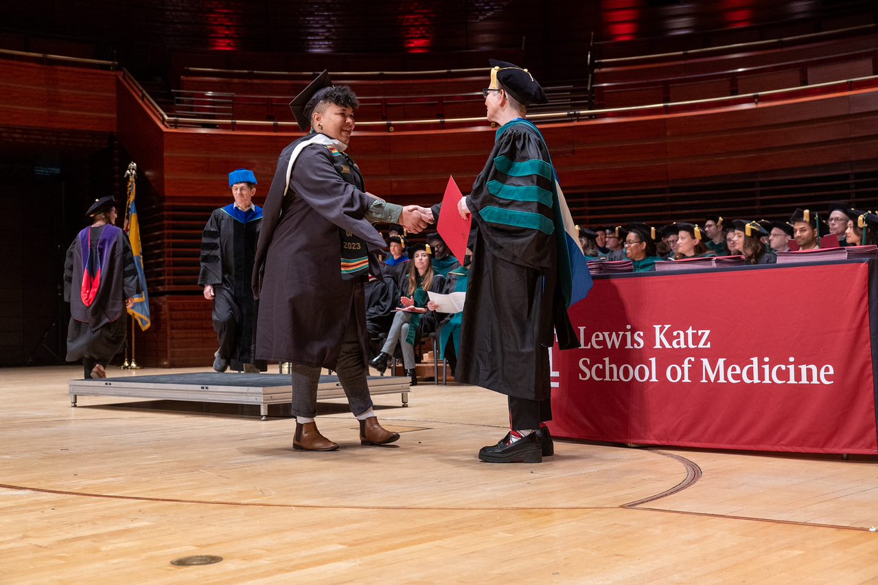 Dr. Amy Goldberg shaking hand and handing a diploma to a graduating student
